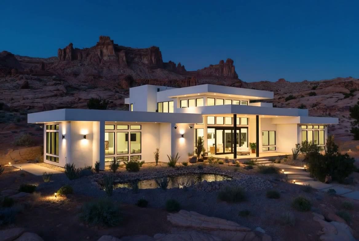 Modern desert home at dusk with warm interior, exterior, and landscape lighting